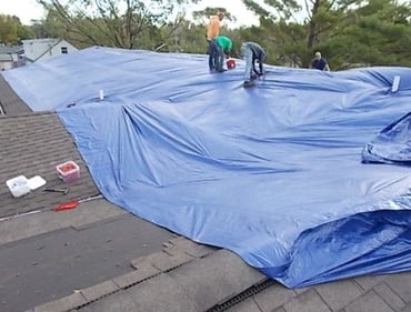 Crew-laying-tarp-on-roof